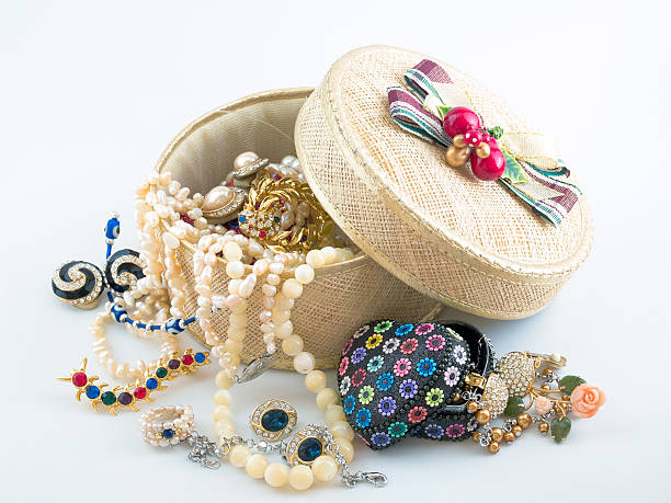 A girl's jewelry and accessories box overflowing with necklaces, brooches, earrings, and other knick knacks.